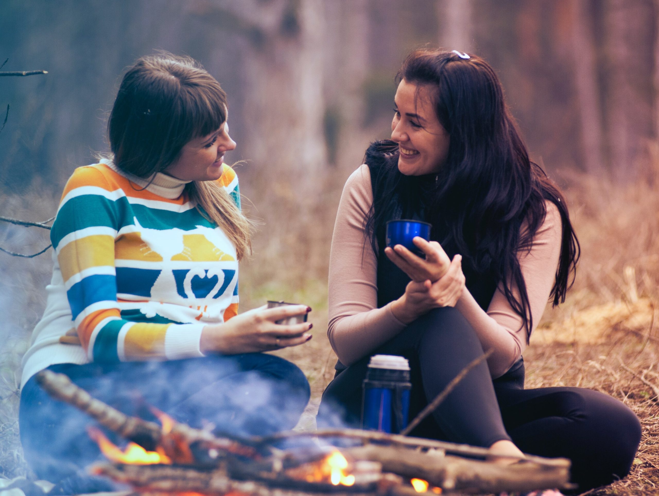 Zwei Frauen unterhalten sich sitzend am Lagerfeuer